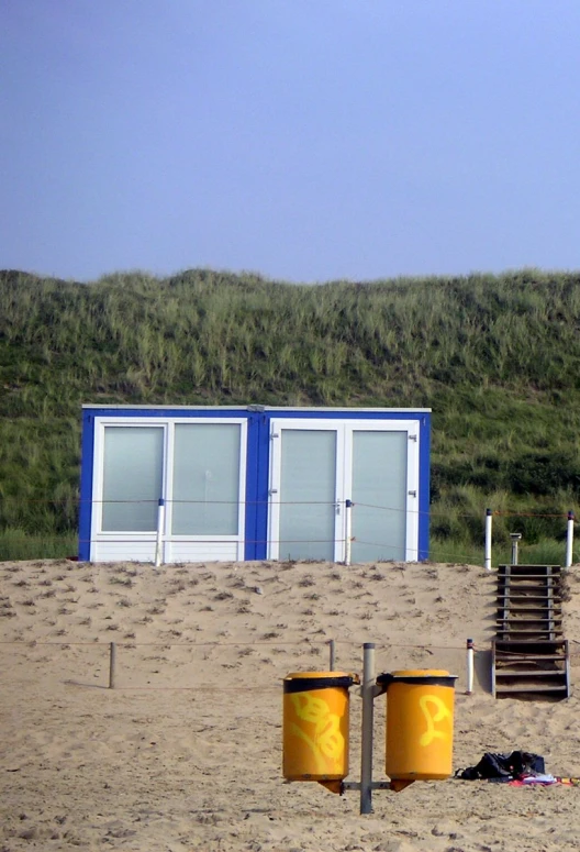 a beach scene with some trash cans and a life guard