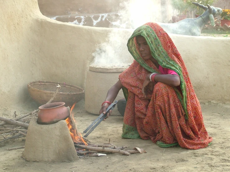 a woman kneeling down to grill some food