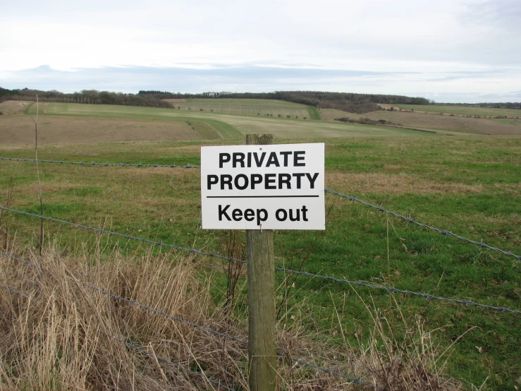 a private property sign near the edge of a green grassy field