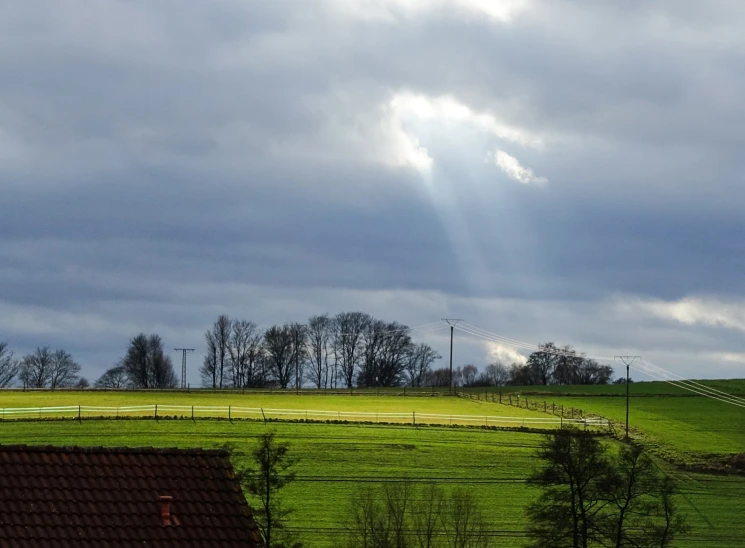 a green field with a light shining through the clouds