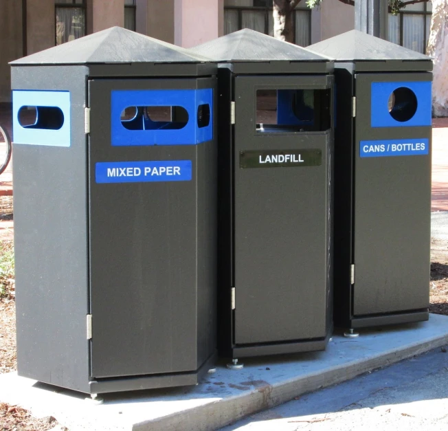 three trash cans outside of a city block