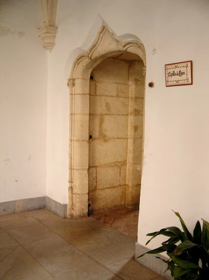 an archway between a wall and a plant in front of it