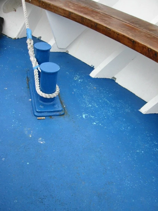 a roped off bucket with blue cups sitting on a boat