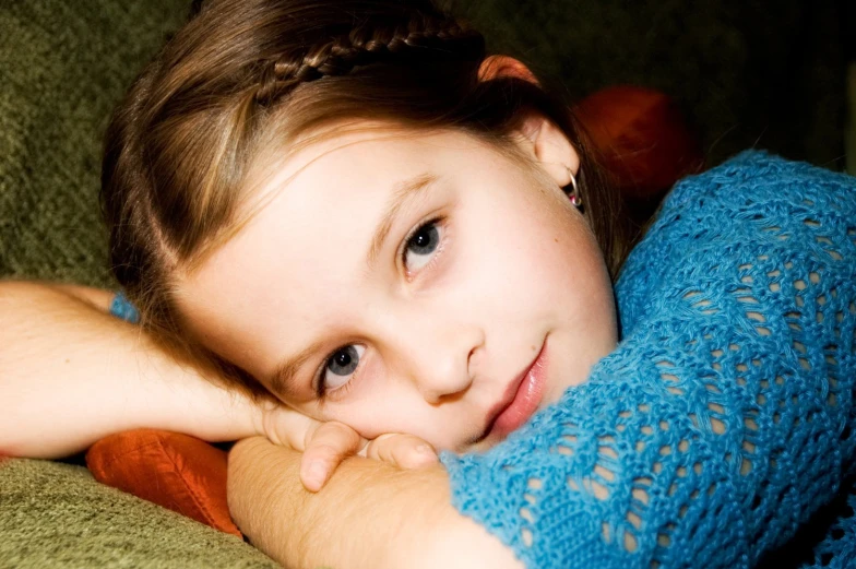 a girl is laying on a green couch with her arm wrapped up