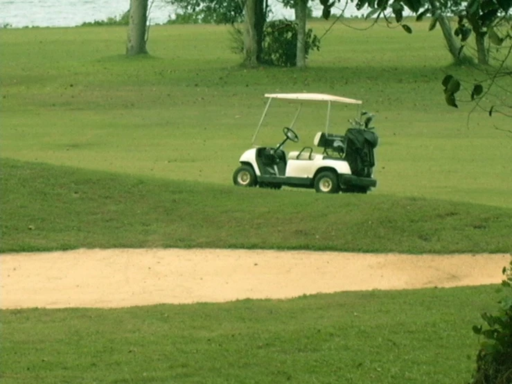 a man is driving a white golf cart across a green field