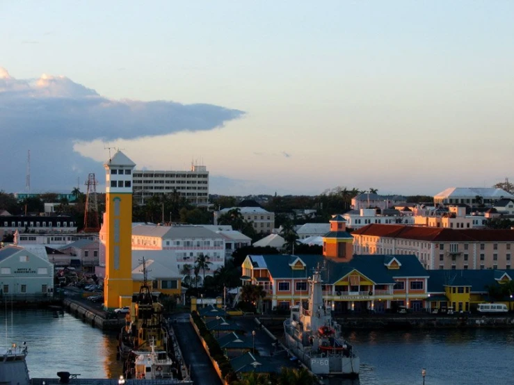 some buildings and a tower near water and clouds