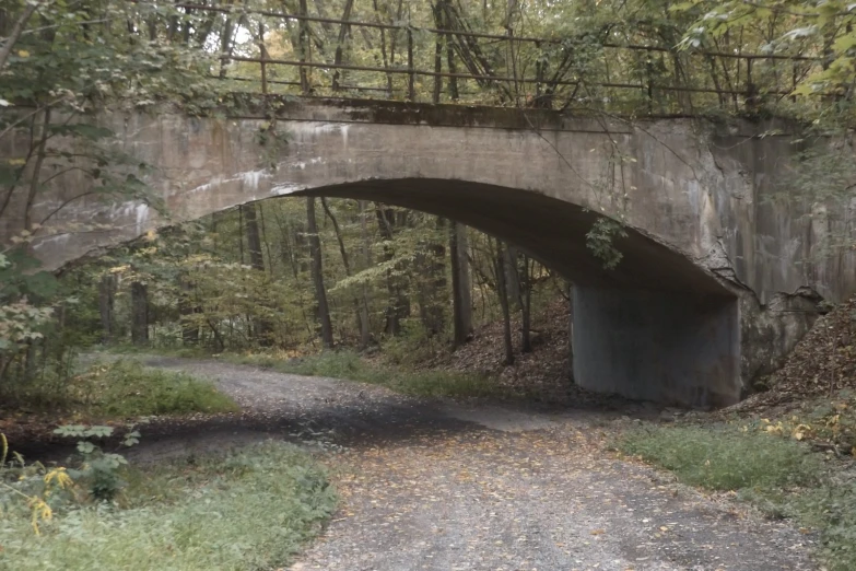 an abandoned road bridge in the woods with dirt and rocks