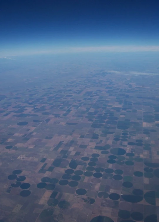 an air plane flying above fields under blue skies