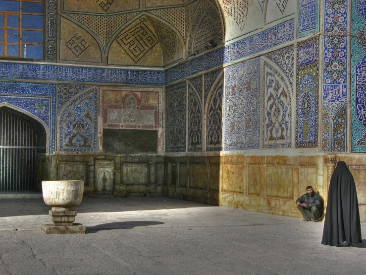 a woman in a mosque sitting down with her back to the camera