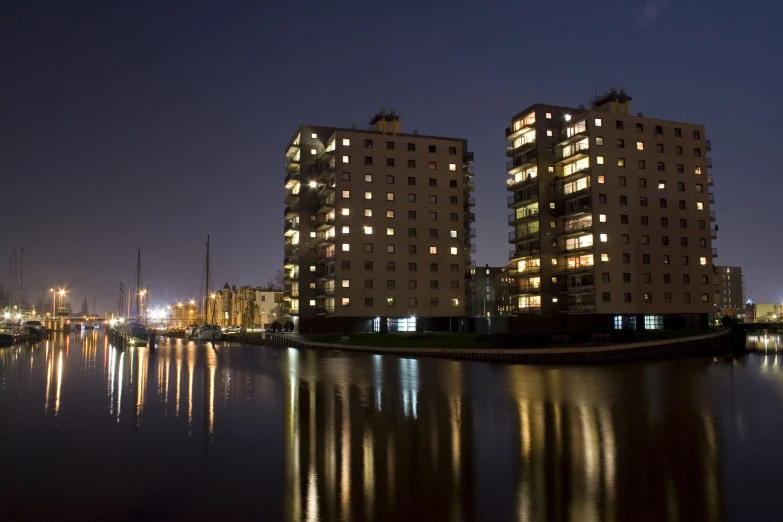 two large buildings lit up by lights on the waterfront