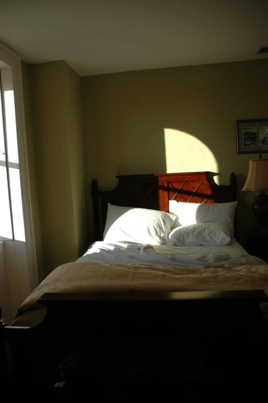 a bed with a light shining through two windows