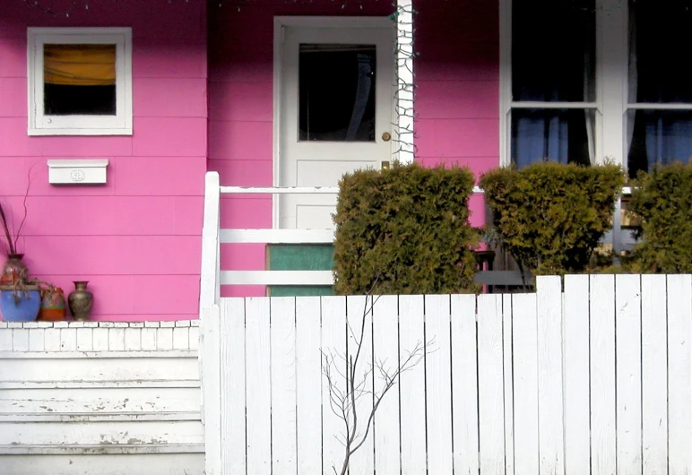 a white fence sitting in front of a pink building