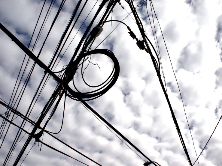 an intersection with wires, poles and a sky filled with clouds