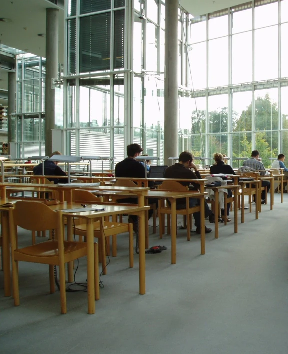 people are seated in a building with long tables and chairs