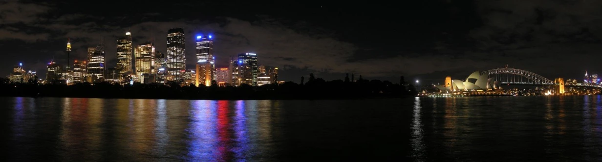 a city skyline at night with a large body of water