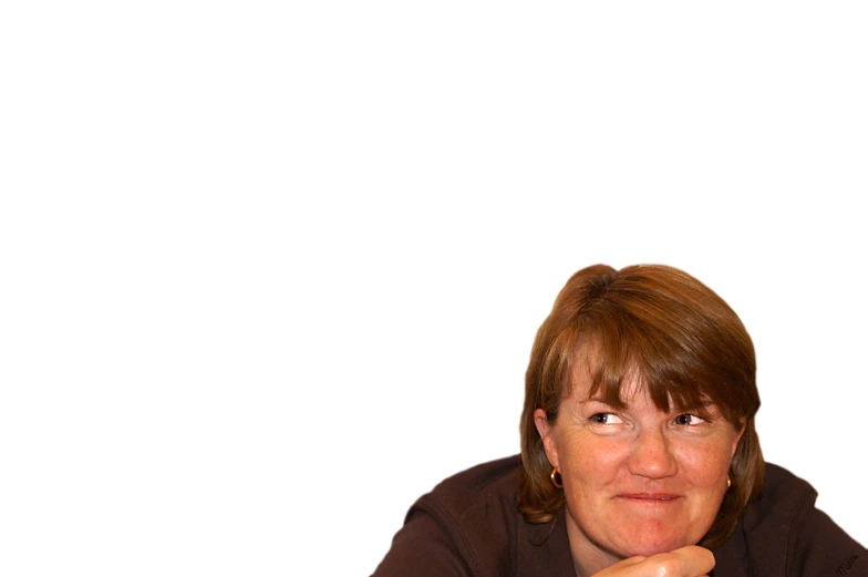 a woman sitting in front of a white wall holding a phone