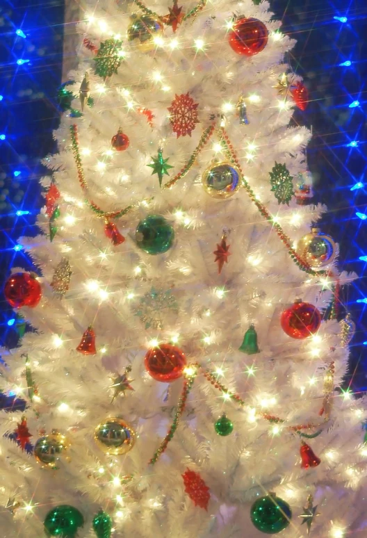 a decorated white christmas tree with lights on
