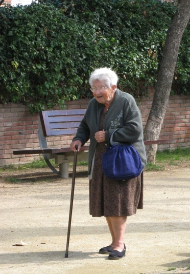 an old woman walking in front of a wooden bench