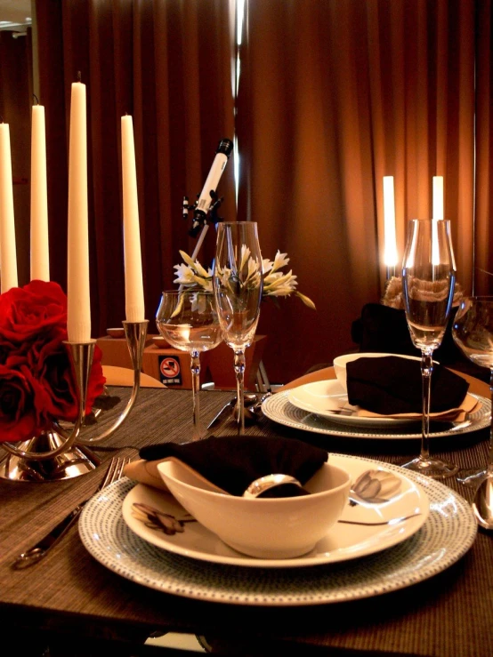 a dinner table set for two with candles and flowers