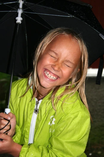 a small girl smiles in the rain with her eyes closed
