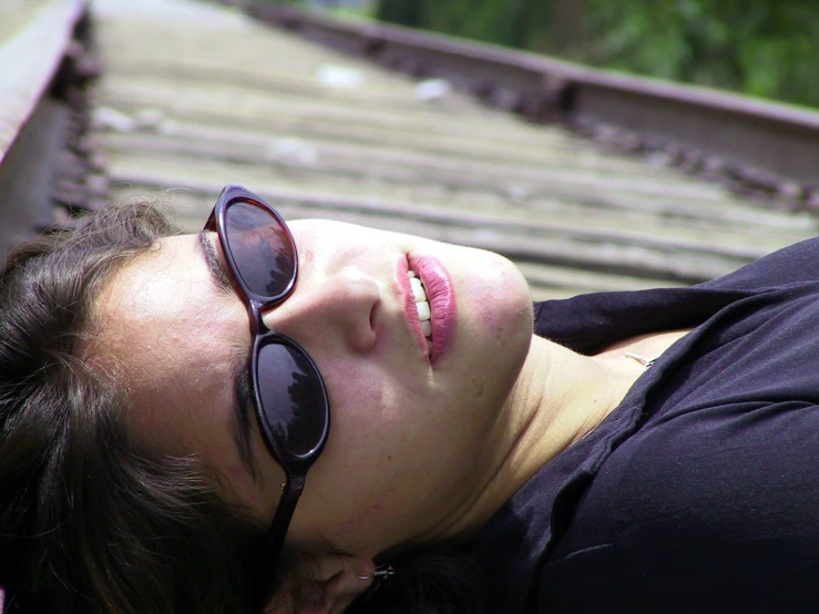 a woman in black laying on a train track