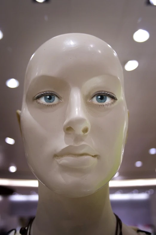 mannequin with a necklace on display behind a white head