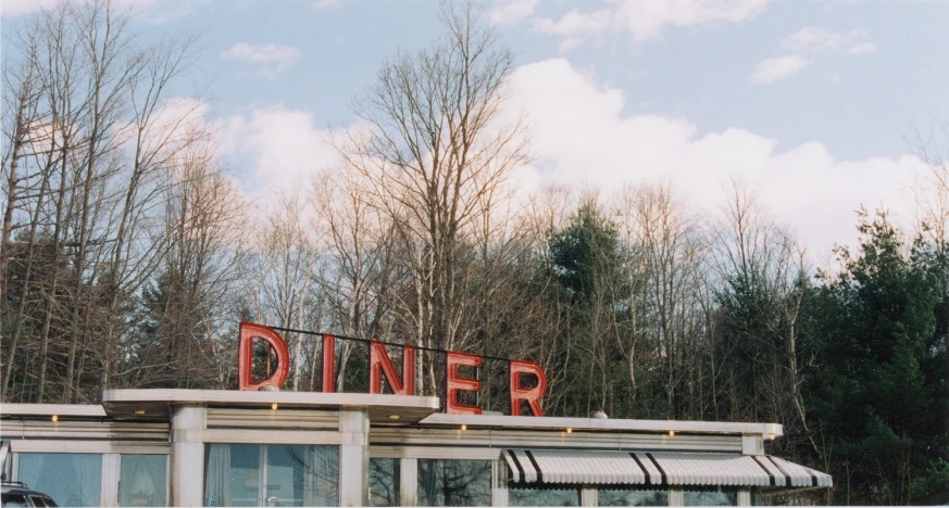 a diner with red letters and a black car