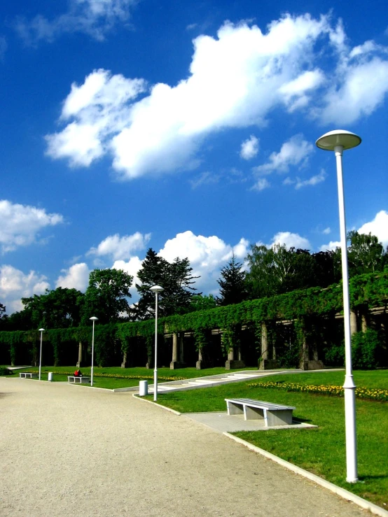 the sidewalk is empty and there are benches in the park