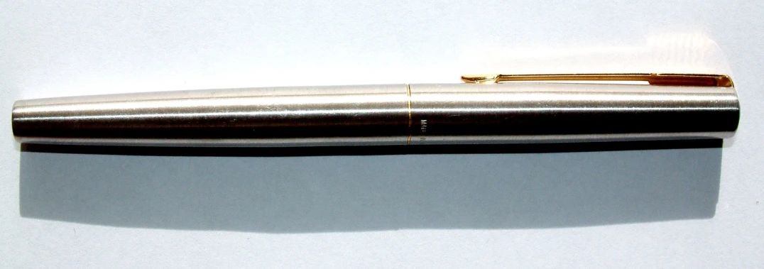 a golden and black pen sitting on a white table