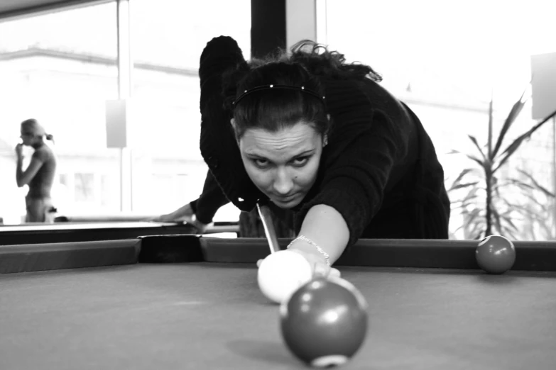 a woman leans down to pick up a pool ball