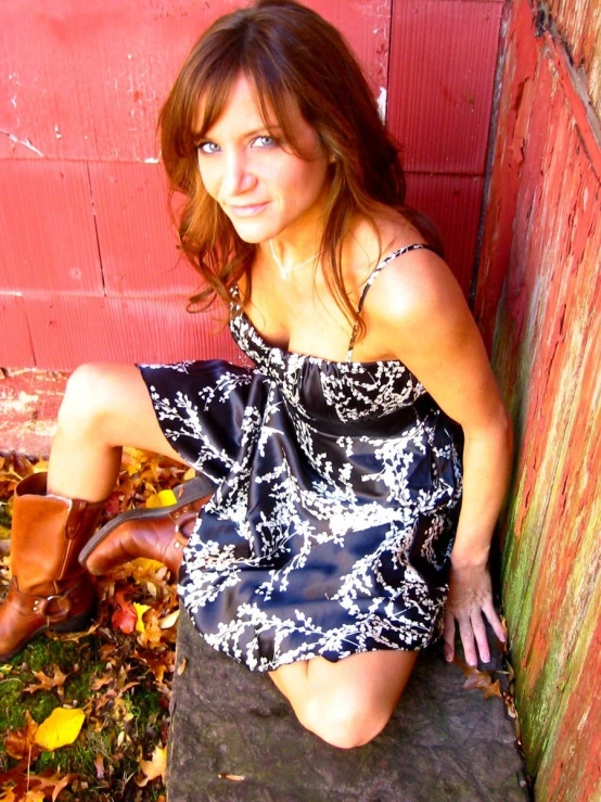 a girl poses in a short dress against a red wall