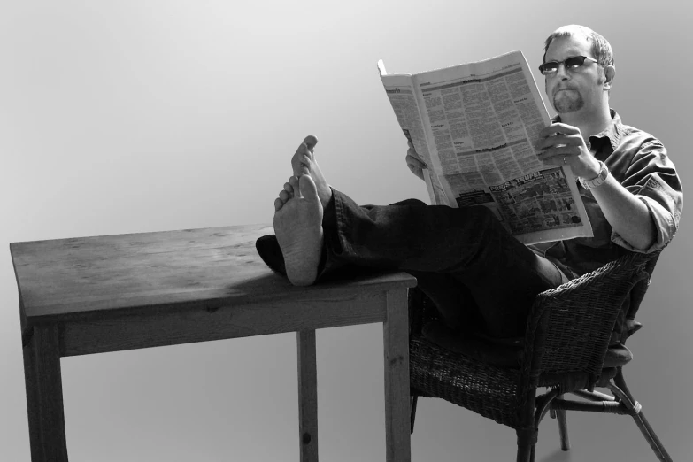 a man reading a newspaper on a chair