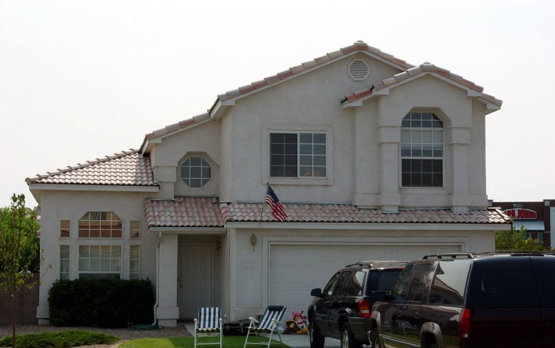 some cars parked in front of a house and a flag