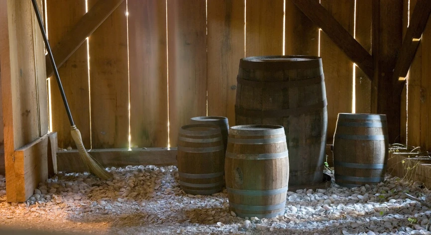 three barrels and two mop sit in front of the wooden fence