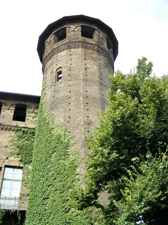 a tall brick tower is seen next to an ivy covered wall