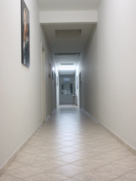 a long corridor with tiled floors and paintings