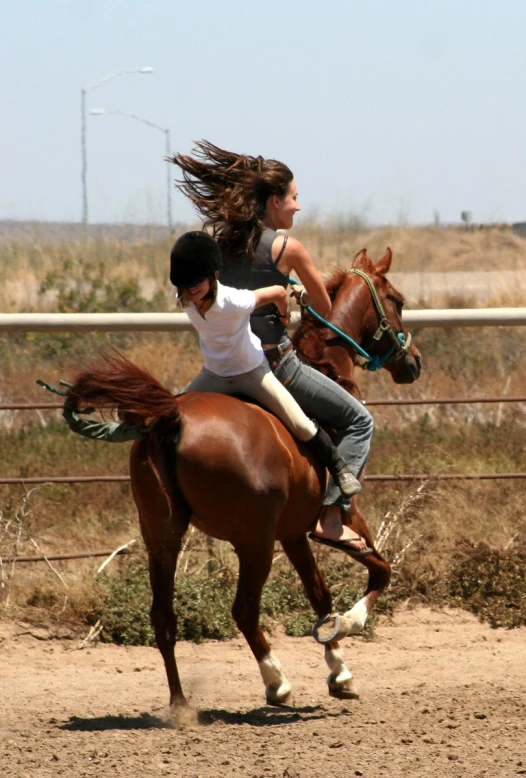 two girls are riding horses in an open area