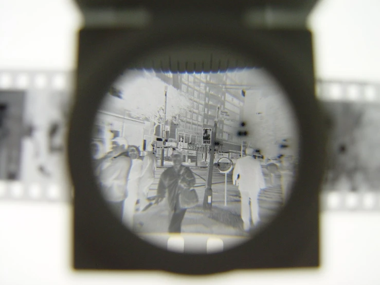 a camera with a view of people on the train track and on the building through the lens