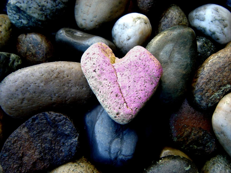 a small pink heart shaped rock laying among some rocks