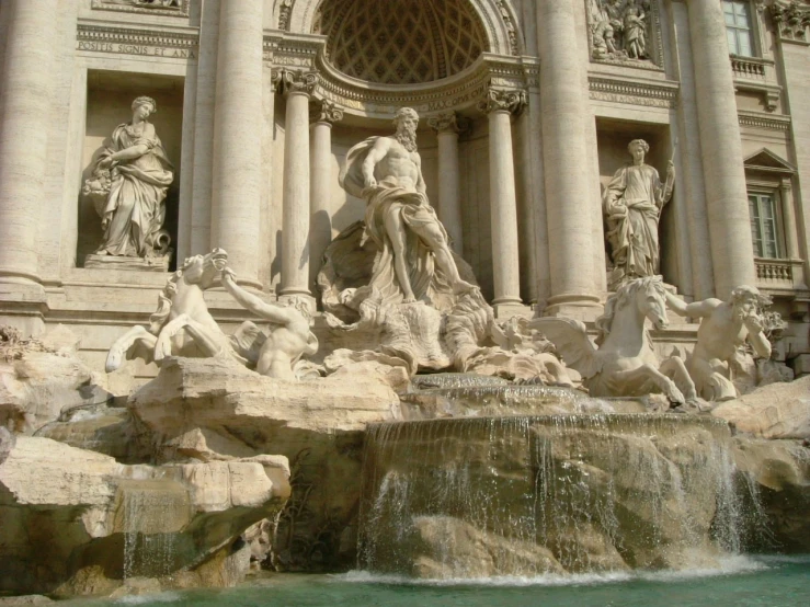 the fountain with statues and fountains on top is water in front of a building
