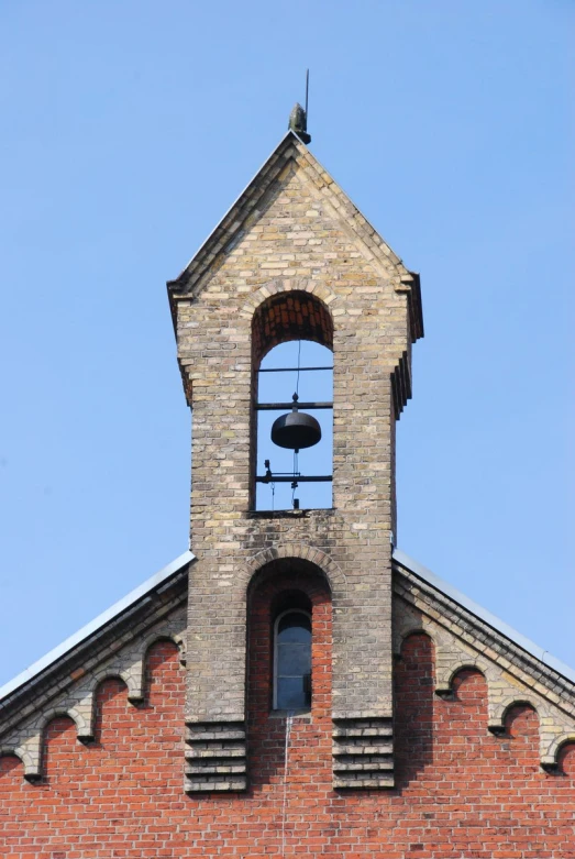 the clock tower on a brick church with a bell