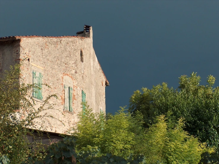 an old stone house with an open window and shutters