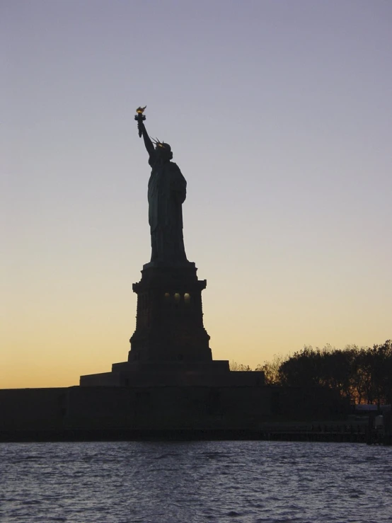 a large statue with a torch lit in front of a city