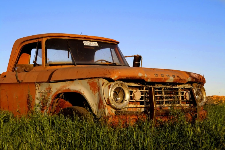 an old rusted pickup truck sits in a field