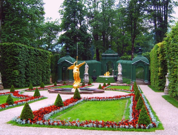 some bushes some trees and a statue and many flowers