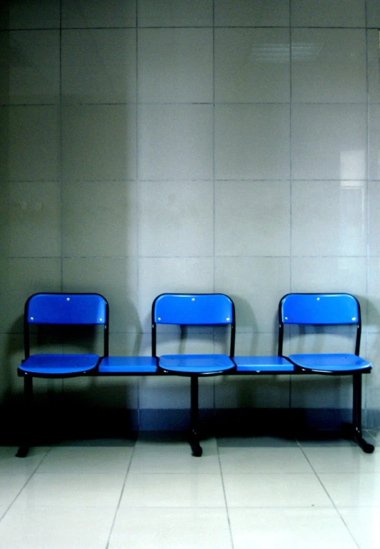 three blue chairs in a row against a wall