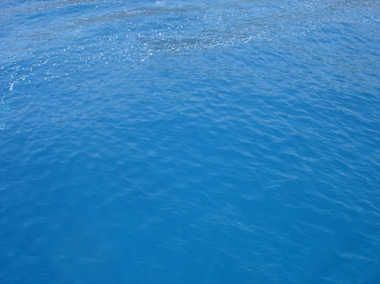 a boat in the blue water in front of a large body of water