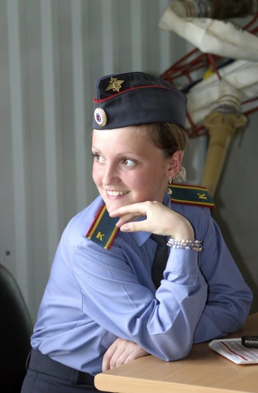 woman in uniform with folded arms sitting at desk