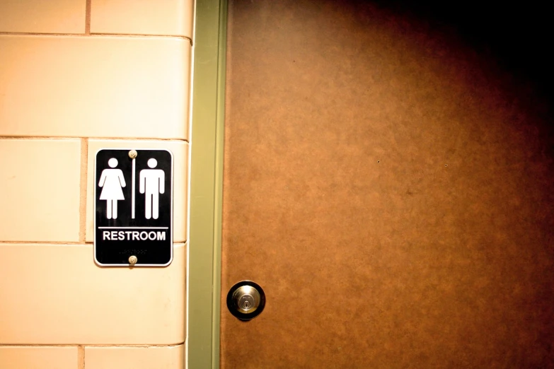 the door to a bathroom is open, showing a sign that warns of urinating