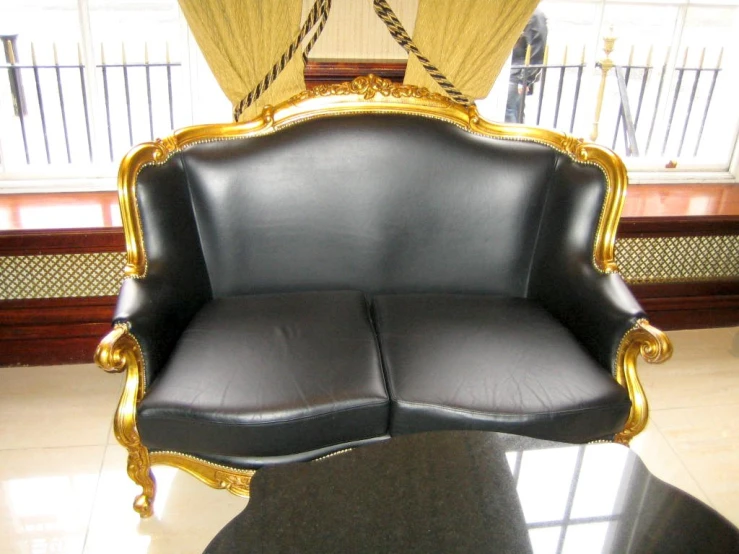 an ornately carved black and gold chair sits in the sun